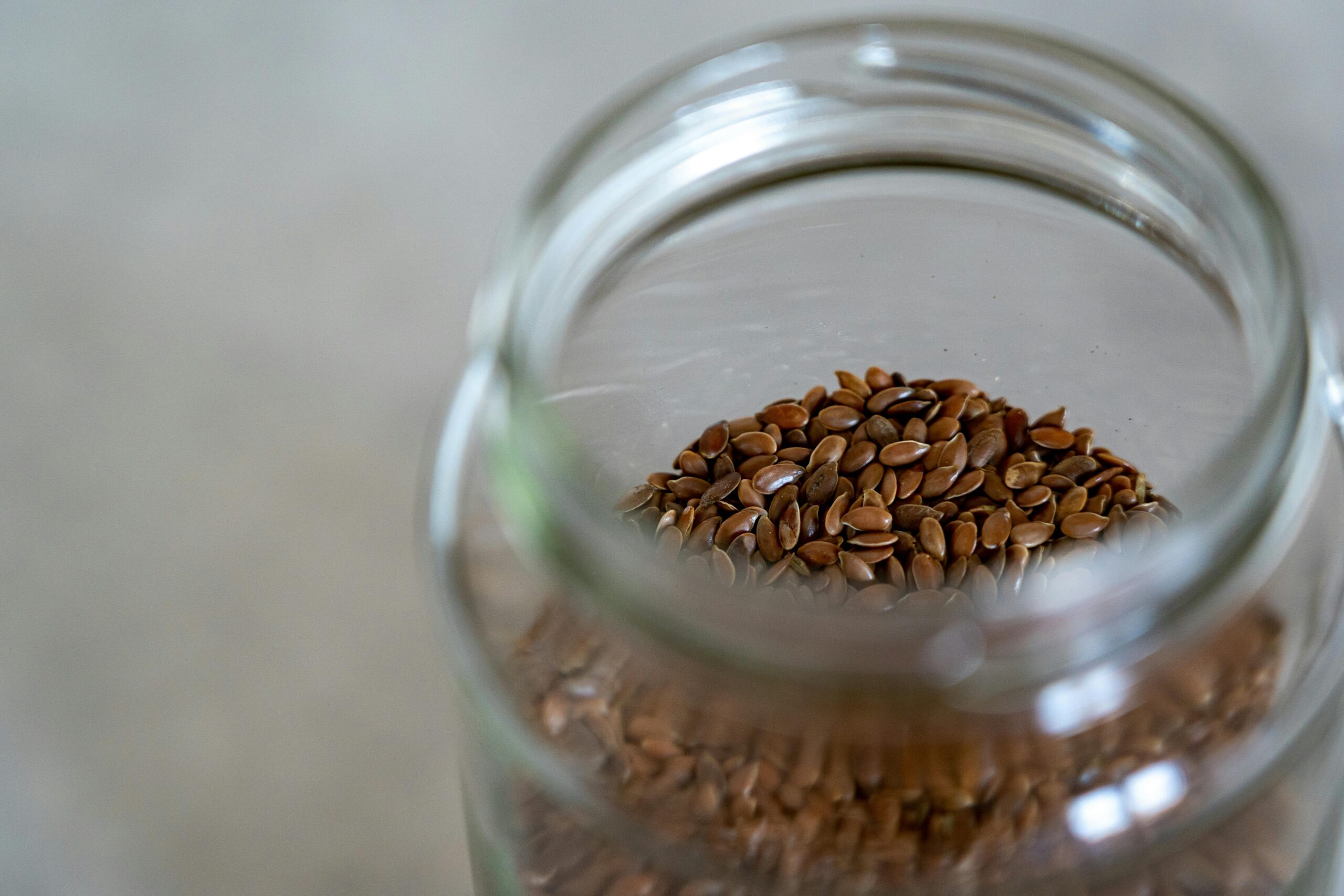 A clear glass jar filled with brown flax seeds, perfect for healthy cooking and baking.